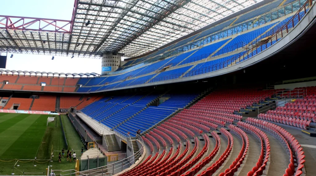 San Siro'nun kavisli tribünleri, kırmızı ve mavi koltuklar ile çatıyı taşıyan kırmızı çelik kiriş
